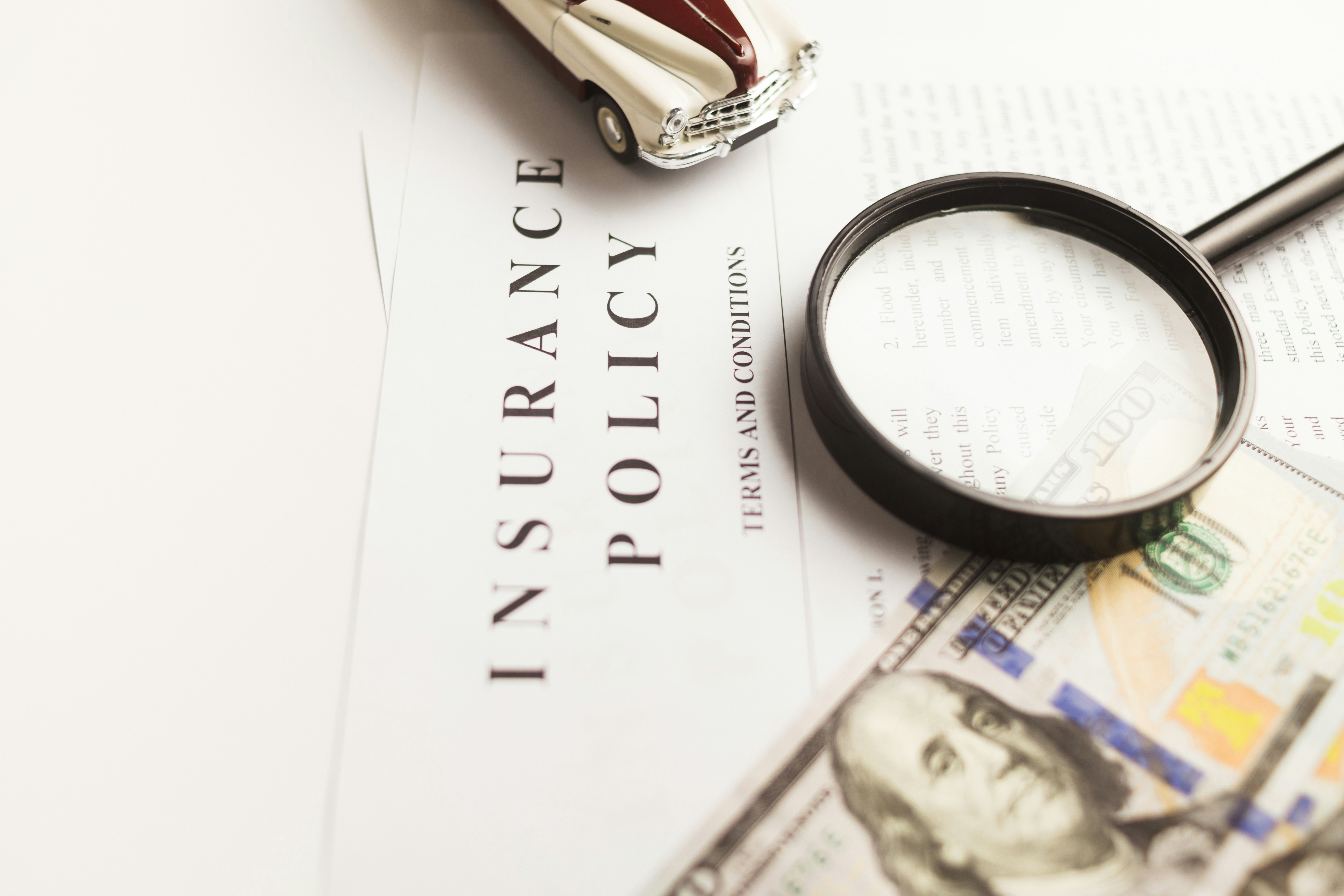 A magnifying glass on top of insurance documents and money
